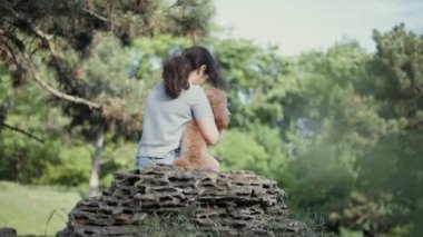 Köpeğini taş parkta oturan genç kadınla. Yavaş motion.ung kadın ile onun köpek park. Ağır çekim.