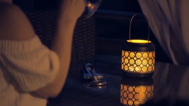 Genç kadın açık terasta beyaz şarap içme. Fener mum gece masada ile  . 