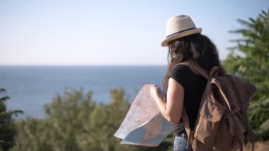 Seyahat ederken harita keşfetmek omuzlarında sırt çantası ile mutlu kadın turist .