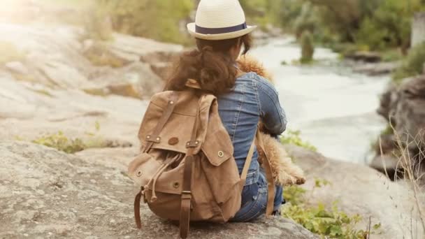女性旅行者のバックパックを犬に押し山川の景色と自然の峡谷を見て — ストック動画