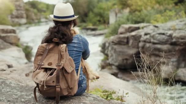 妇女旅行者与背包藏品狗并且看在自然峡谷以山河的看法 — 图库视频影像