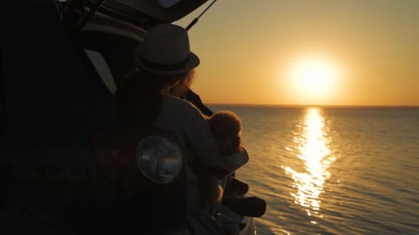 Podróżnik Kobieta Psem Siedząc Bagażniku Samochodu Pobliżu Morza Oglądając Zachód — Wideo stockowe