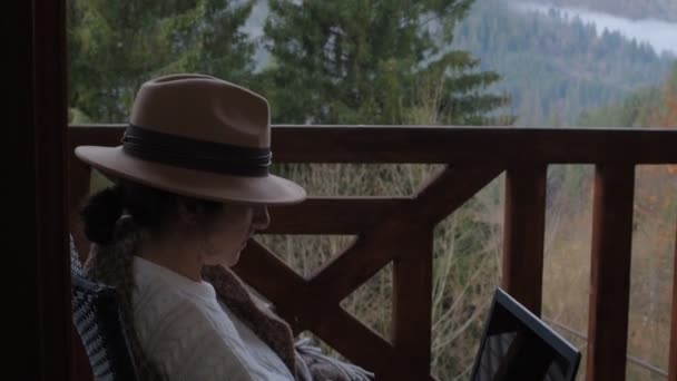 Γυναίκα Ταξιδιώτης Κάθεται Στην Βεράντα Ένα Δισκίο Ενάντια Όμορφο Ορεινό — Αρχείο Βίντεο