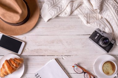 Seyahat natürmort ayrıntıları. Kahve, şapka, telefon, vintage fotoğraf makinesi ve kazak üzerine ahşap masa.