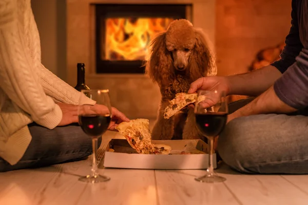 Young couple have romantic dinner with pizza and wine over fireplace background. Romantic concept .
