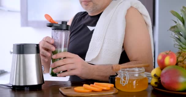 トレーニングの後の家庭の台所で成人男性飲むスムージー — ストック動画