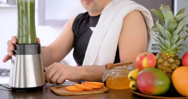 成人男性の家庭の台所でジュース マシンでトレーニングの後緑のジュースを作って — ストック動画