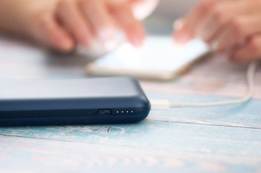 Güç bankaya şarj ederken akıllı telefon kullanan kadın.