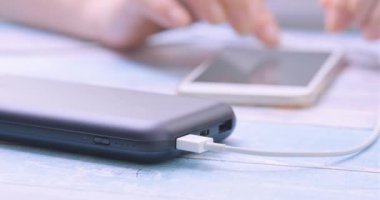 Güç bankaya şarj ederken akıllı telefon kullanan kadın.