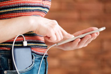 Güç bankaya şarj ederken akıllı telefon kullanan kadın.