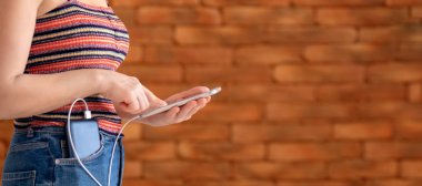 Güç bankaya şarj ederken akıllı telefon kullanan kadın.