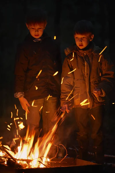 İki erkek ellerini ateşin yanında, sıcak oturup ve ateşe bakmak