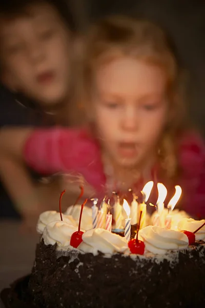 Birthday of the elder brother. A boy with a younger sister blows out candles on a birthday cake