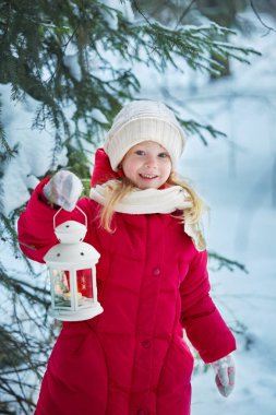 Küçük kız bir el feneri elinde tutmak ve gülümseyerek. Kış, açık havada