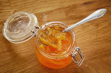 Kaşığı Portakal Reçeli bir cam kavanoza var. Ahşap masa. 