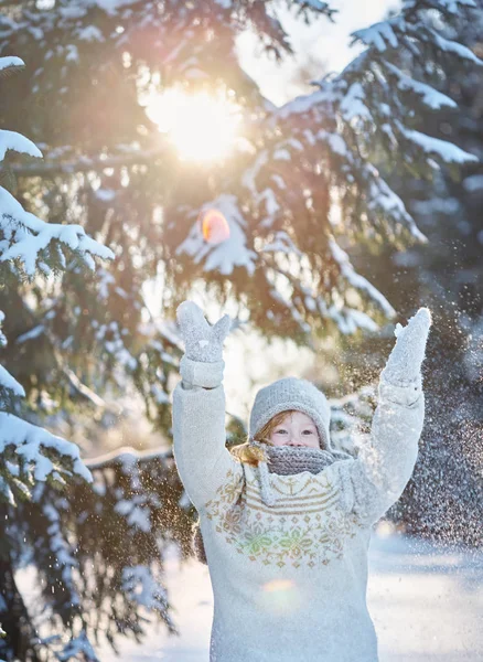 戴着雪帽 围巾和毛衣的快乐小女孩把雪扔了出来 — 图库照片