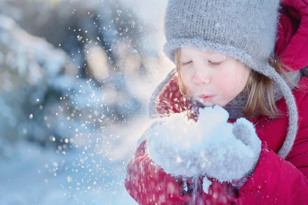 在雪地上吹着红色外套的小女孩 — 图库照片