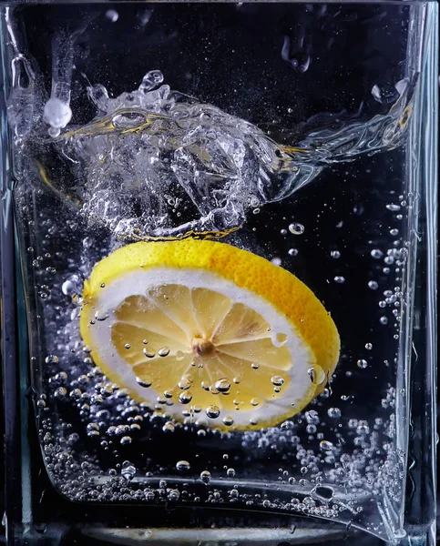 Pezzo di limone in un vaso di vetro. Fondo nero — Foto Stock