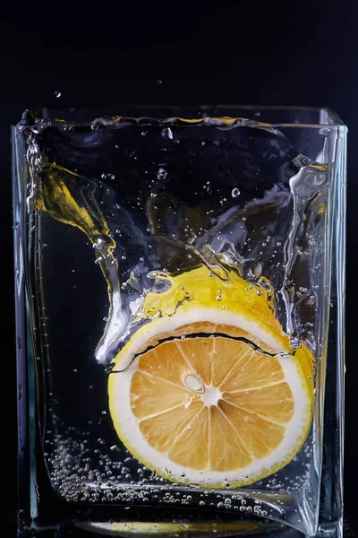 Morceau de citron dans un récipient en verre. Fond noir — Photo