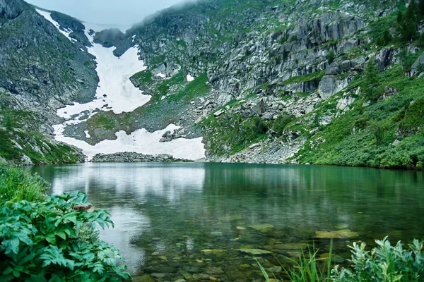 Paysage montagneux. Lac bleu et champ de neige sur le rivage — Photo