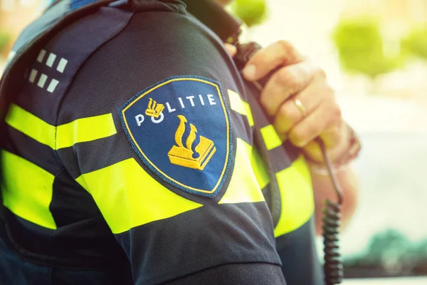 Police néerlandaise avec la main sur la radio. Focus sur badge — Photo