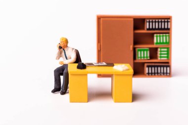 Çalışma masasının arkasında oturan minyatür iş adamı. Tiny People iş konseptinin makro çekimi.