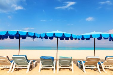 Mavi plaj şemsiye ve şezlong kumlu sahil üzerinde. Tatil tatil arka plan ve plaj kavramı.