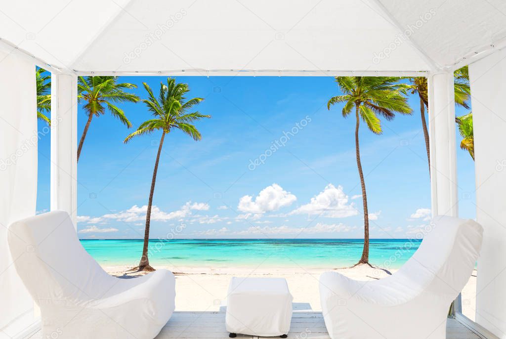 View of the beautiful beach through a Balinese bed. White sandy beach of a luxury resort in Punta Cana, Dominican Republic.