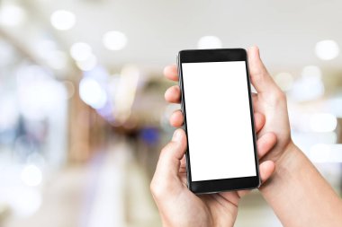 Adamın eli cep telefonuyla bulanık alışveriş merkezinin arka planında boş ekran..
