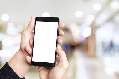 Adamın eli cep telefonuyla bulanık alışveriş merkezinin arka planında boş ekran..