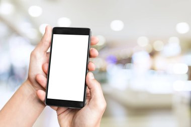 Adamın eli cep telefonuyla bulanık alışveriş merkezinin arka planında boş ekran..