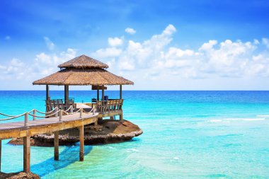 Mavi bulutlu gökyüzünün altında, Koh Kood, Tayland 'da hindistan cevizi palmiyesi yapraklarıyla dolu bir deniz. Tatiller ve turizm konsepti. Tropik Tatil Köyü.