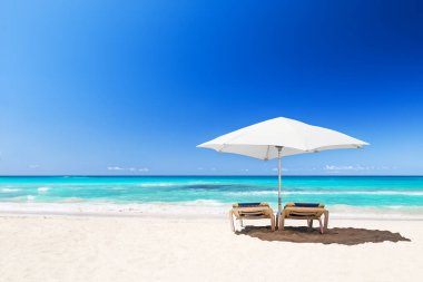 Beyaz şemsiyeli plaj sandalyeleri ve Punta Cana, Dominik Cumhuriyeti 'ndeki güzel kumsal plajı..