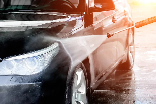 Yüksek basınçlı su kullanarak arabayı temizlemek. Elle oto yıkama, basınçlı su, dışarıda araba yıkama. Seçici odak.