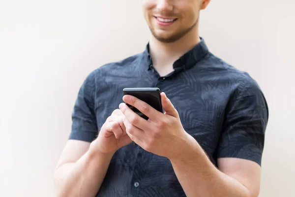 Man using mobile smart phone, close up. Picture of young man using a mobile smart phone and smiling.