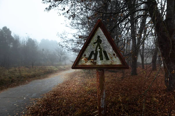 Поврежденный пешеходный знак на лесной дороге — стоковое фото