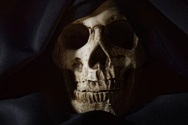 Closeup photo an old skull covered in black robe — Stock Photo, Image