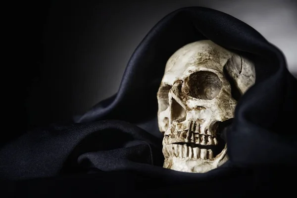 Closeup photo an old skull covered in black robe — Stock Photo, Image