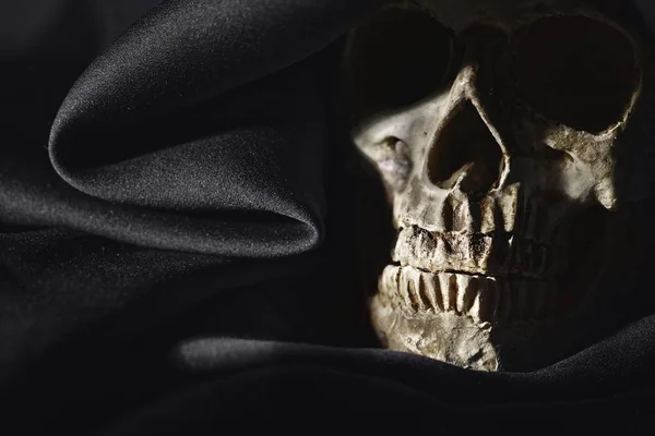 Nahaufnahme Foto eines alten Totenkopfes in schwarzer Robe — Stockfoto