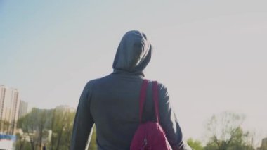 Genç bir kız spor çantasını özel bir takım elbiseyle tutuyor. Arkadan yakın çekim görüntüsü.