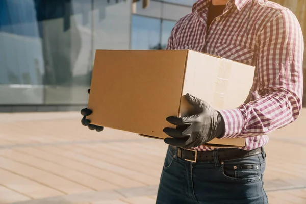 男子的双手戴着黑色一次性手套 特写镜头中握着一个纸板箱 解雇后从工作中捡东西的概念 — 图库照片
