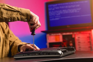 Bozuk bilgisayar ekipmanlarını tamir etmek için tornavidayı yakın çekimde tut. Parçalar için işlemci sökülüyor.