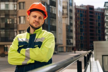 Genç, yakışıklı, gülümseyen bir mimar inşaat planlarını denetliyor..
