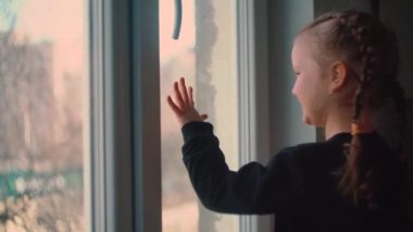 Çocuk pencereden dışarı bakıyor. Sıkılmış Karen Coronavirüs 'ü görüyor.