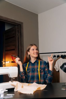 Terzi kadın iş yerinde gözlük tutuyor. Gözler uzun çalışmaktan yoruldu. Görüşü bozma kavramı