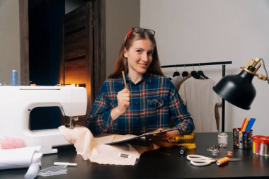 Terzi, müşteri verilerinin ölçümlerini kaydetmek için bir kalem tutuyor. Küçük işletmeler bireysel terzilik başvurularını kabul ederler