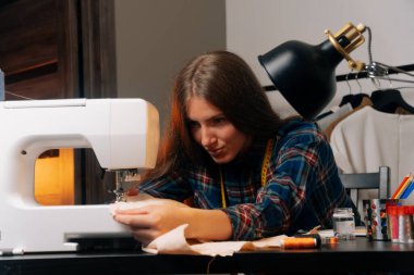 Dikiş tasarımcısı dikiş makinesine dikiş diker. Küçük ev kavramı..