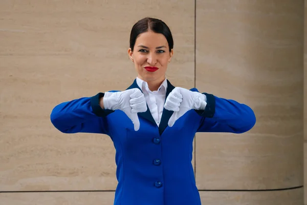 Tricky girl flight attendant shows indignation dislike. Flight attendant in white gloves indignant, thumbs down. High quality photo