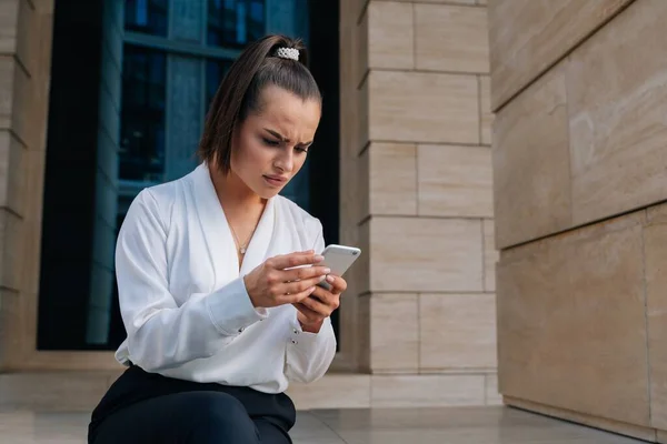 Una Joven Hermosa Mira Teléfono Inteligente Sentado Fondo Oficina Plan — Foto de Stock