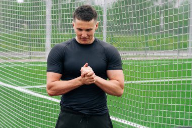 Spor fiziği olan bir adamın portresi stadyumun kapısında duruyor. Açık hava sporları konsepti.